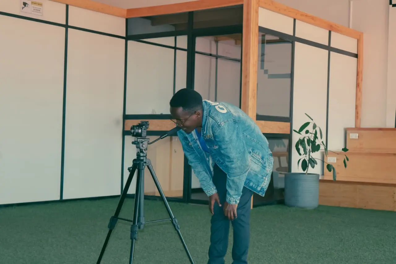 Ian Asena bent to the viewfinder of a camera on a tripod, his face hidden behind the lens