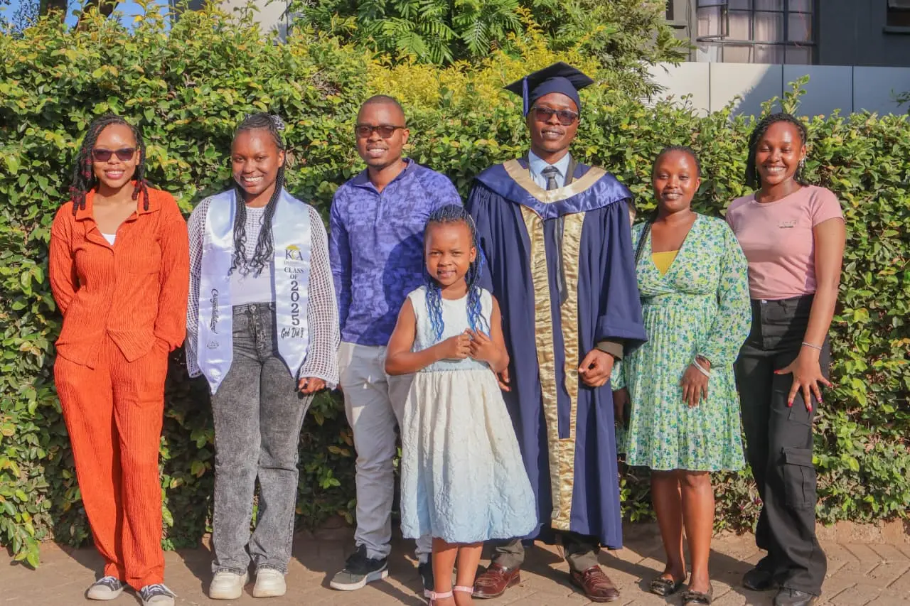 A graduate surrounded by smiling friends in bright colours, one wearing a Class of 2025 sash